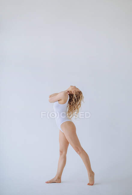 Turnerin im weißen Trikot tanzt in einem Studio — Stockfoto