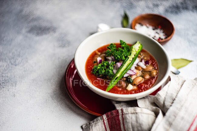 Cuenco de sopa de tomate picante y frijol con chile verde fresco y guarnición de perejil - foto de stock