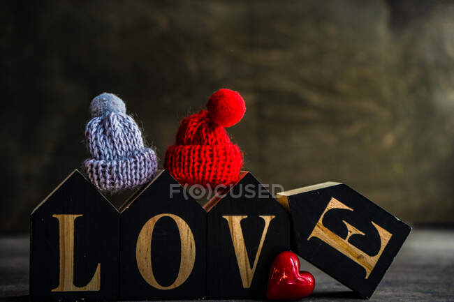 Corazón de madera con una cinta roja sobre un fondo negro - foto de stock