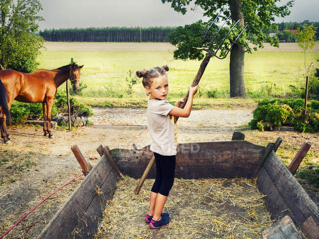 Girl standing in a wagon holding a pitchfork, Poland — Stock Photo