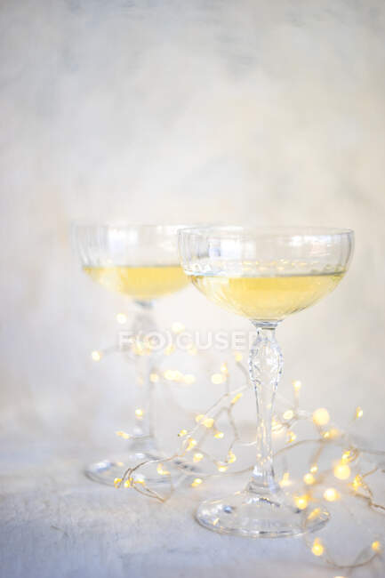 Два келихи шампанського з казковими вогнями на столі — стокове фото
