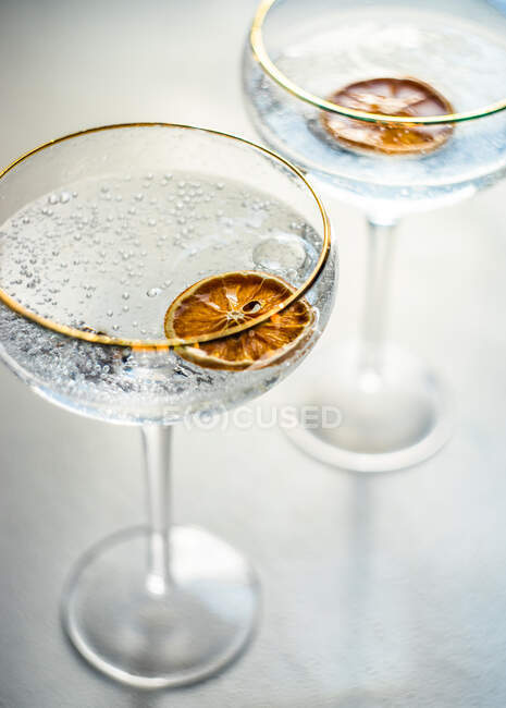 Overhead view of two glasses of champagne with slices of dried orange — Stock Photo