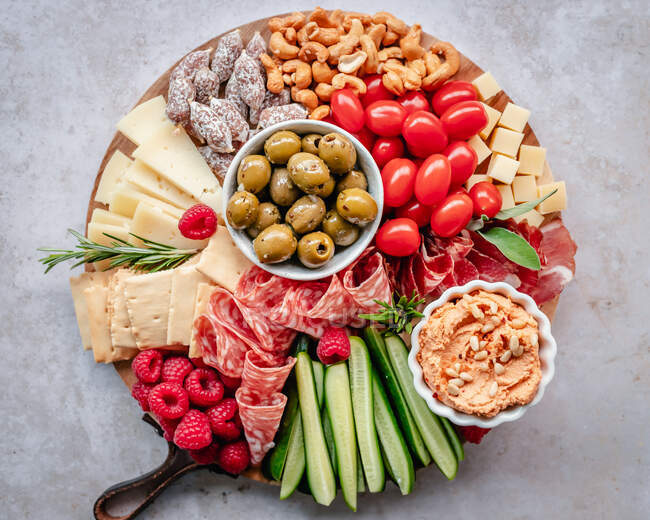 Charcuterie et plateau de fromage avec houmous, noix, fruits et légumes — Photo de stock