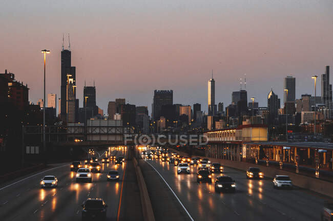 Міський скайлайн і автомобілі їдуть по автостраді на заході сонця, Чикаго, Іллінойс, США. — стокове фото