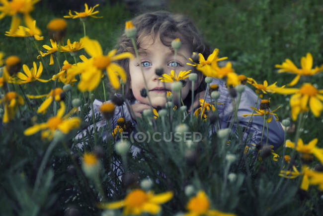 Portrait of a girl hiding behind flowers in a garden, Italy — Stock Photo
