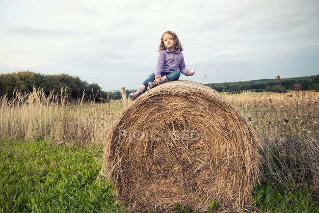 Mädchen sitzt auf einem Heuballen auf einem Feld in Polen — Stockfoto