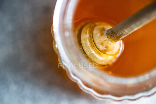 Honey dipper in a glass of organic honey — Stock Photo