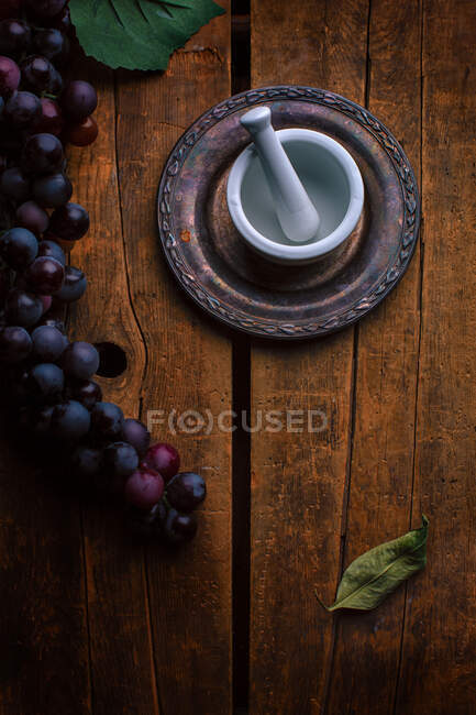Bunch of grapes next to a mortar and pestle on a wooden table — Stock Photo