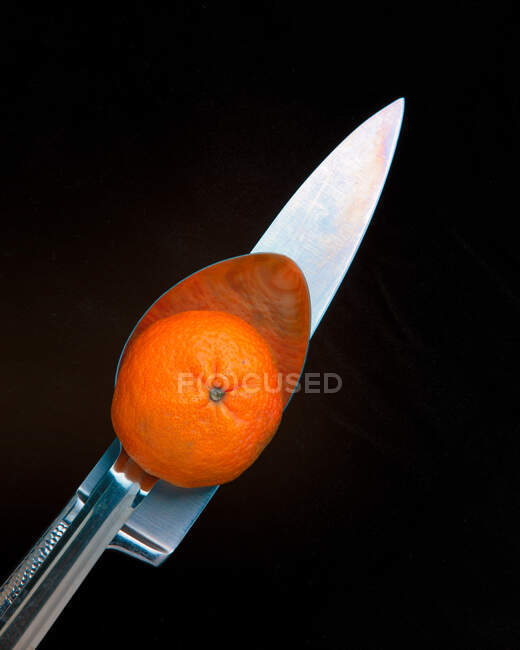Vista aérea de una mandarina sobre una cuchara y un cuchillo - foto de stock