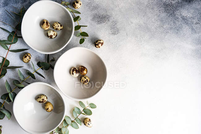 Пасхальный стол с чашами пасхальных яиц и стеблей эвкалипта — стоковое фото