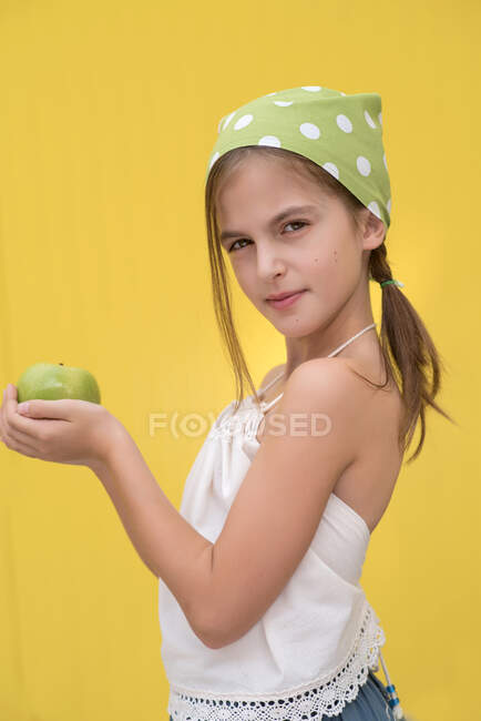 Retrato de uma menina usando um lenço verde bolinha ponto segurando uma maçã verde — Fotografia de Stock