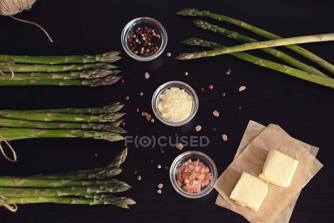 Overhead view of asparagus, butter, parmesan cheese, salt and pepper — Stock Photo