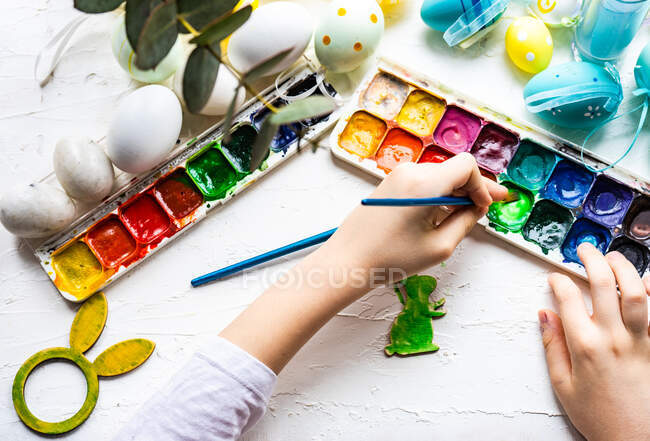 Overhead view of a boy's hands painting an Easter bunny decoration — Stock Photo