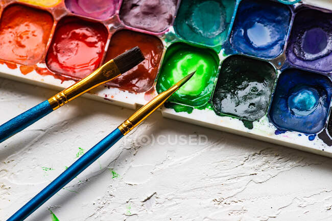 Due pennelli e una tavolozza con colori ad acquerello — Foto stock