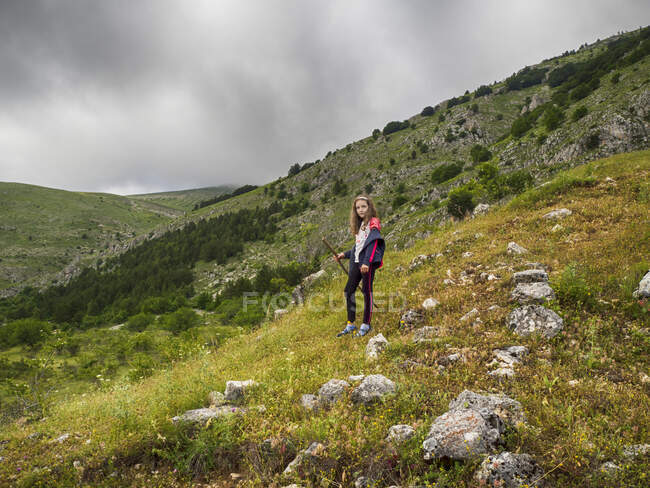 Ragazza in piedi nel paesaggio rurale in possesso di un bastone, Italia — Foto stock