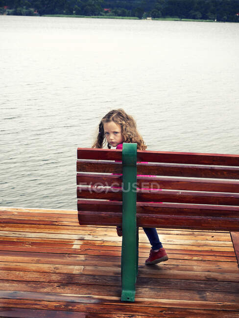 Visão traseira de uma menina sentada em um banco olhando por cima de seu ombro, Polônia — Fotografia de Stock