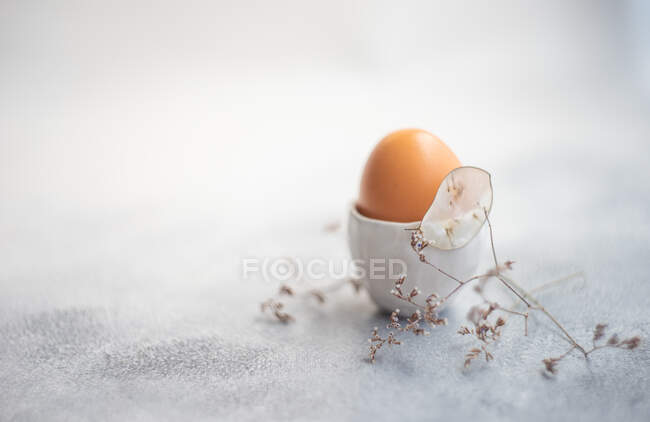 Boiled egg in egg cups next to dried flowers — Stock Photo