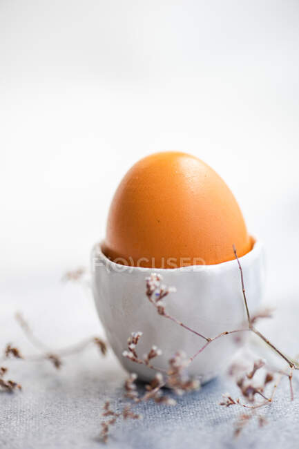 Boiled egg in an egg cup next to dried flowers — Stock Photo