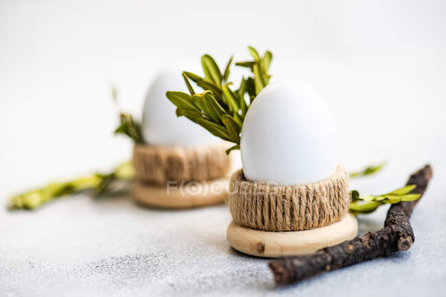 Two boiled eggs in egg cups with boxwood leaves — Stock Photo