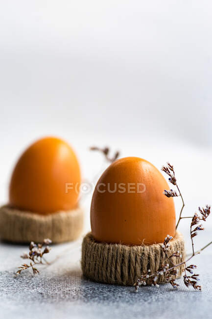 Два вареных яйца в яичных чашках рядом с сушеными цветами — стоковое фото