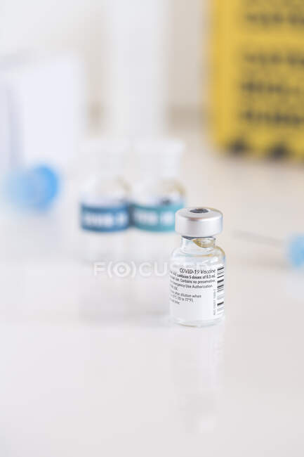 Um frasco para injetáveis da vacina contra o Coronavirus e seringa numa mesa de uma clínica — Fotografia de Stock