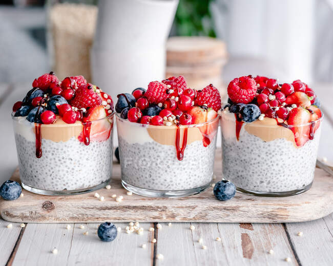 Three chia puddings with yogurt, mixed berries, peanut butter and syrup — Stock Photo