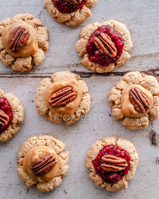 Blick auf Erdnussbutter-Daumenabdruck-Kekse mit Marmelade, Karamell und Pekannüssen — Stockfoto