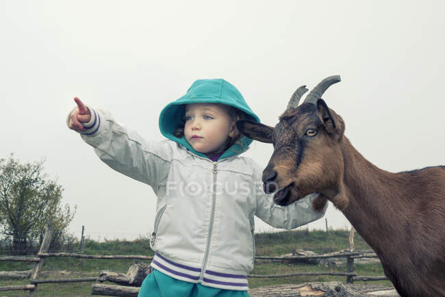 Girl standing next to a goat pointing, Poland — Stock Photo