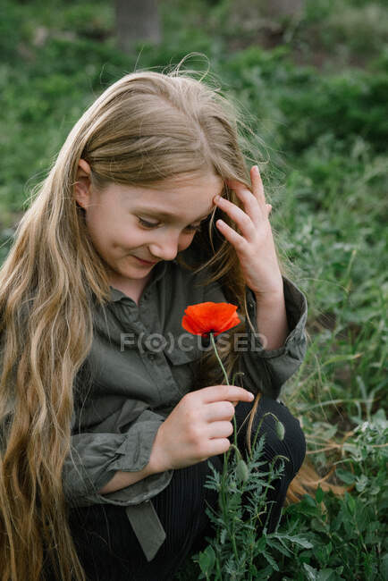 Retrato de uma menina de pé em um campo segurando uma papoula, Rússia — Fotografia de Stock