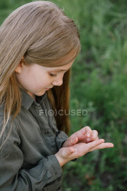 Retrato de uma menina olhando para um inseto na mão, Rússia — Fotografia de Stock