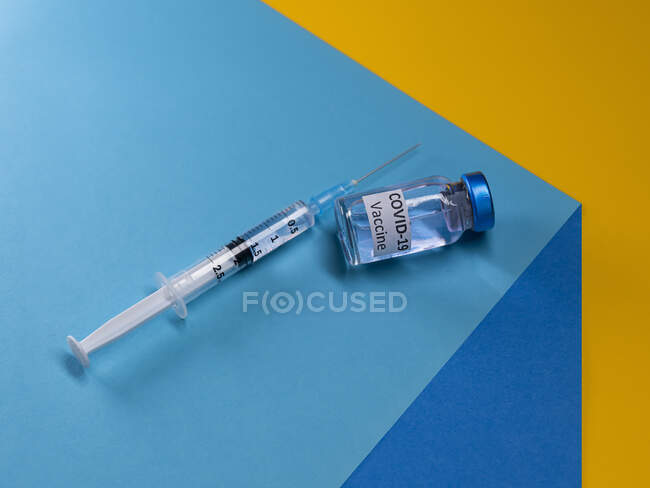 Vacuna y jeringa de Covid-19 sobre una mesa - foto de stock