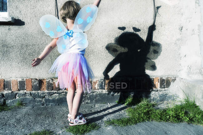 Mädchen im Feenkostüm, das Schatten auf eine Wand wirft — Stockfoto