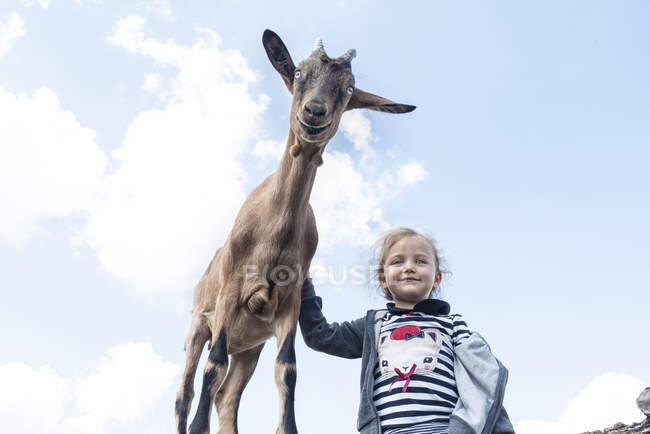 Portrait of a Girl stroking a goat, Poland — Stock Photo