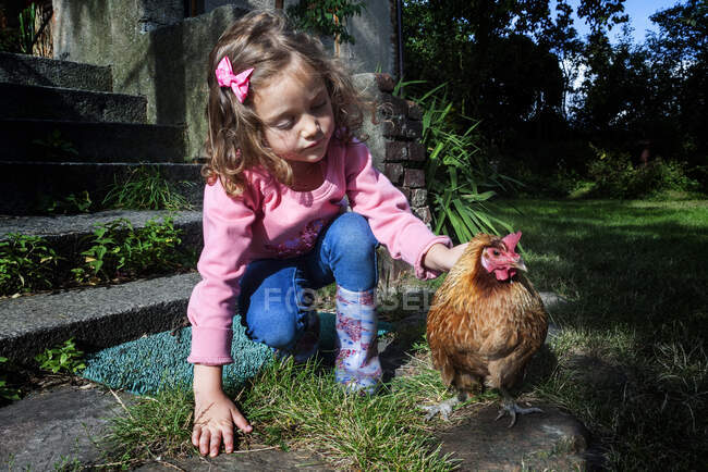 Chica acariciando un pollo - foto de stock