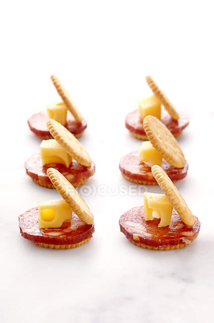 Three salami and cheese crackers in a row — Stock Photo