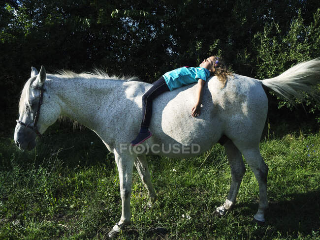 Menina deitada em um cavalo relaxante ao sol, Polônia — Fotografia de Stock