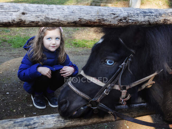 Портрет девушки, приседающей у лошади — стоковое фото