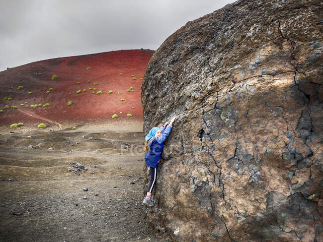 Girl hanging off a giant rock, Lanzarote, Canary Islands, Spain — Stock Photo