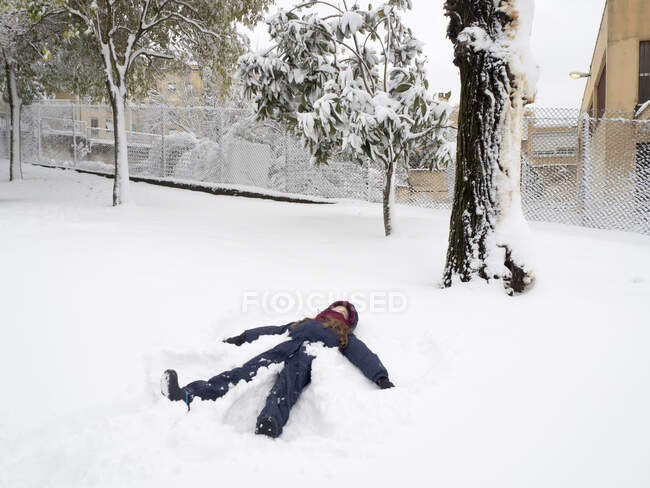 Ragazza sdraiata sulla neve che fa un angelo della neve, Roma, Lazio, Italia — Foto stock