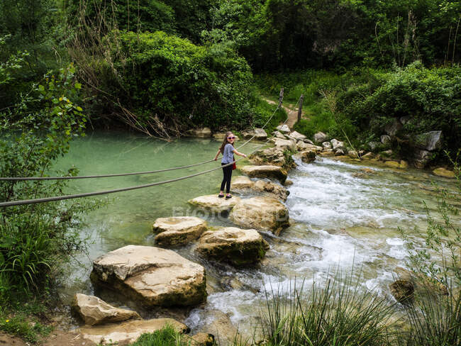 Girl walking across rocks in a river, Tuscany, Italy — Stock Photo