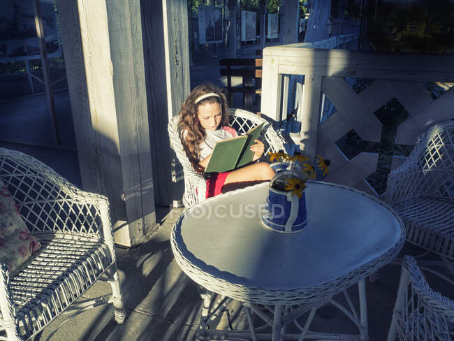 Ragazza seduta su una terrazza a leggere un libro — Foto stock