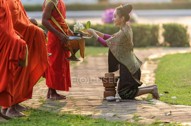 Mulher ajoelhada diante de três monges oferecendo esmola, Tailândia — Fotografia de Stock