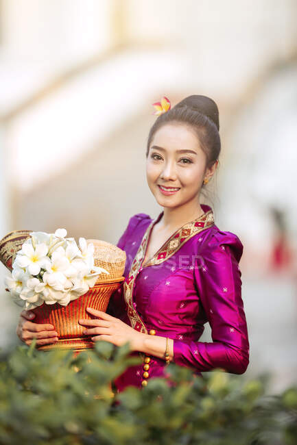 Portrait d'une belle femme tenant un panier avec des fleurs fraîches, Thaïlande — Photo de stock