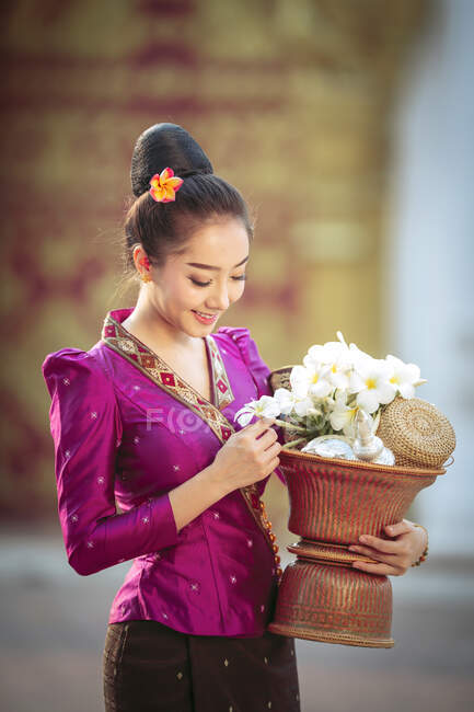 Portrait of a beautiful woman holding a basket with fresh flowers, Thailand — Stock Photo