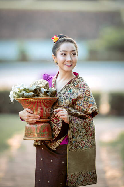 Retrato de una hermosa mujer sosteniendo una cesta con flores frescas, Tailandia — Stock Photo