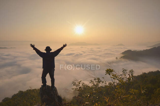 Silhouette of a man standing on a mountain above cloud carpet, Thailand — Stock Photo