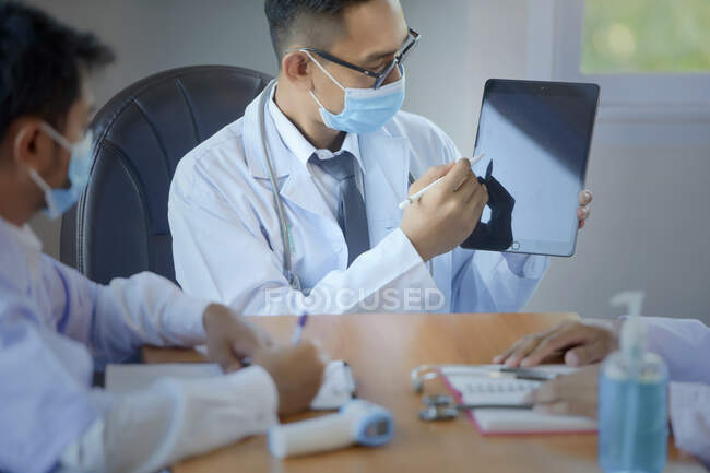 Tres doctores sentados en una oficina teniendo una reunión, Tailandia - foto de stock
