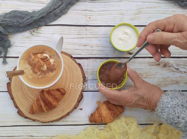 Donna che si gode una tazza di caffè con croissant freschi, salsa di cioccolato e crema — Foto stock