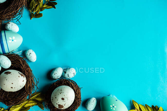 Ovos de Páscoa pintados e decorações de ninhos de pássaros em um fundo azul — Fotografia de Stock