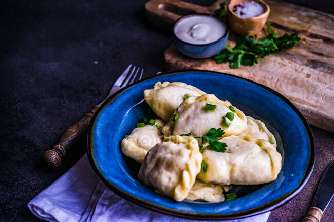 Украинские вареники картофельные пельмени с чивым гарниром и сметаной — стоковое фото